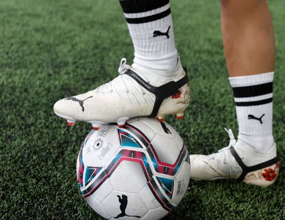 Cityplay tracker on a white football boot controlling a football