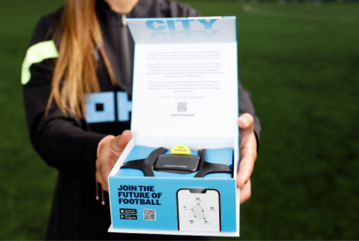 female soccer player holding a gift box containing playermakers soccer tracker