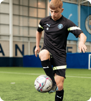 Footballer in the Manchester City indoor training ground controlling a football with his right boot